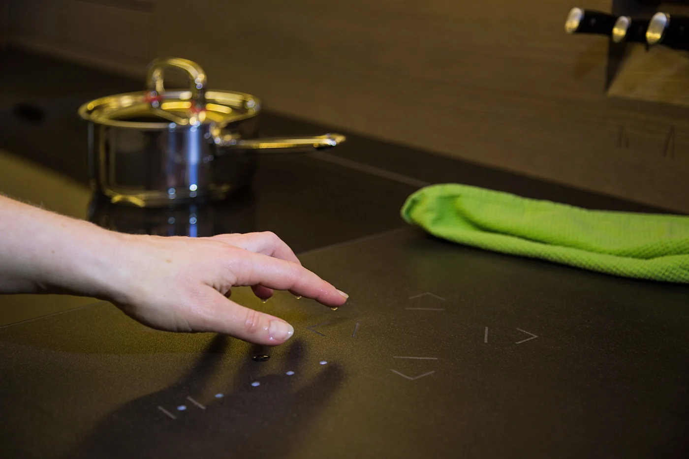 Mão a utilizar um comando Loxone Touch Stone integrado na bancada da cozinha